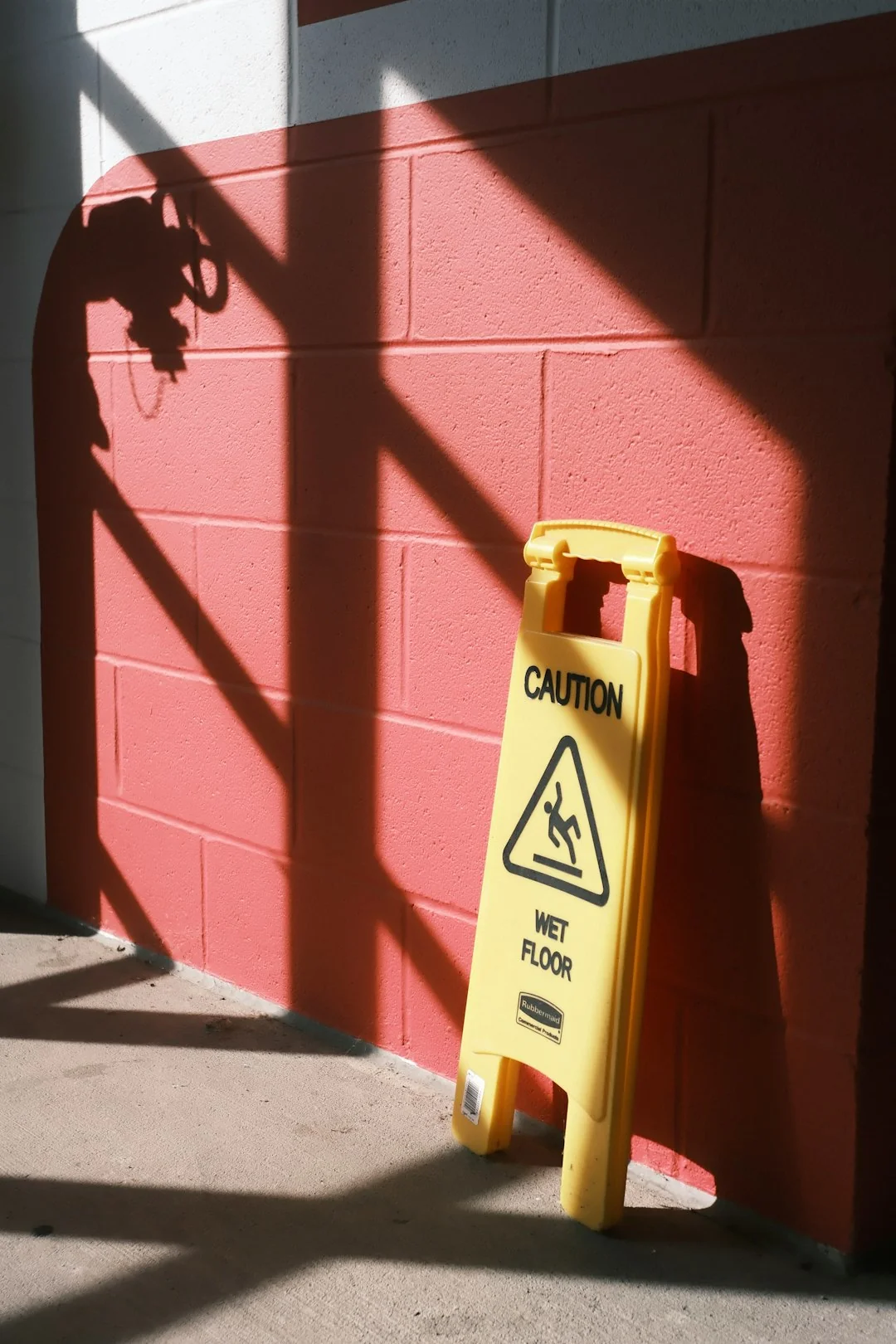 A brightly lit industrial hallway with a cleaning cart and supplies near an office door.